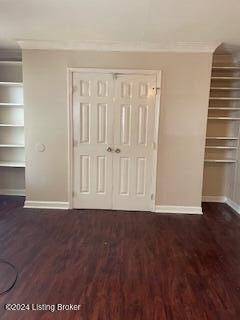 unfurnished bedroom featuring a closet, crown molding, and dark hardwood / wood-style flooring