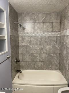 bathroom featuring tiled shower / bath combo, a textured ceiling, and toilet