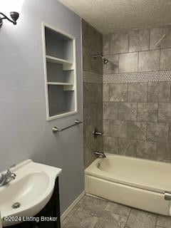 bathroom featuring vanity, tiled shower / bath combo, and a textured ceiling