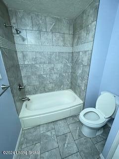 bathroom with toilet and tiled shower / bath