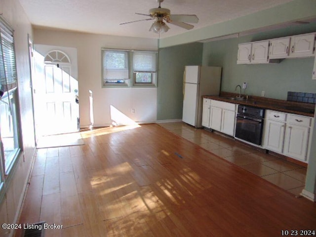 kitchen with white fridge, light wood-type flooring, plenty of natural light, and white cabinets