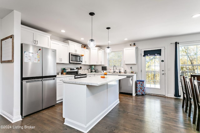 kitchen featuring a wealth of natural light, a center island, decorative light fixtures, and stainless steel appliances