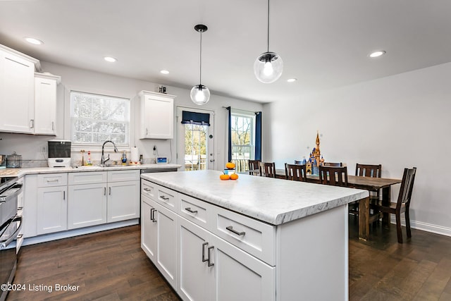 kitchen featuring dark hardwood / wood-style flooring, white cabinets, a center island, and pendant lighting