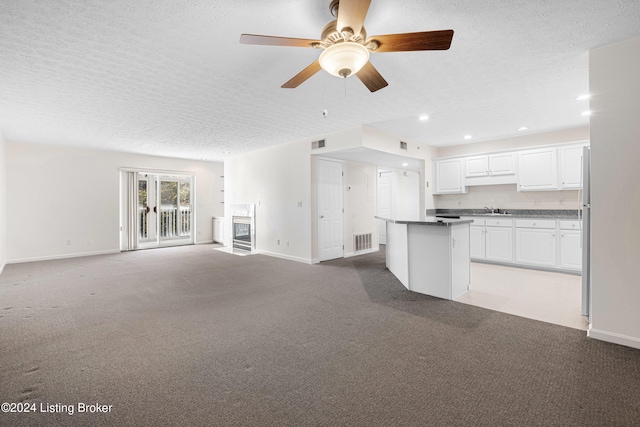 unfurnished living room with light carpet, a textured ceiling, sink, and ceiling fan