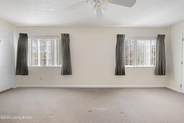 carpeted spare room with a textured ceiling, a healthy amount of sunlight, and ceiling fan