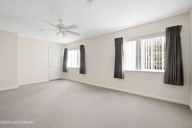 unfurnished room with a textured ceiling, light colored carpet, and ceiling fan