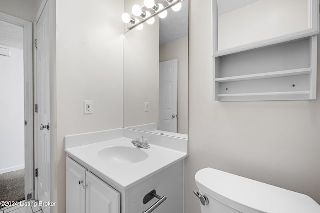 bathroom featuring vanity, a textured ceiling, and toilet