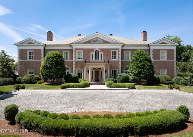 greek revival inspired property featuring a balcony and a front lawn