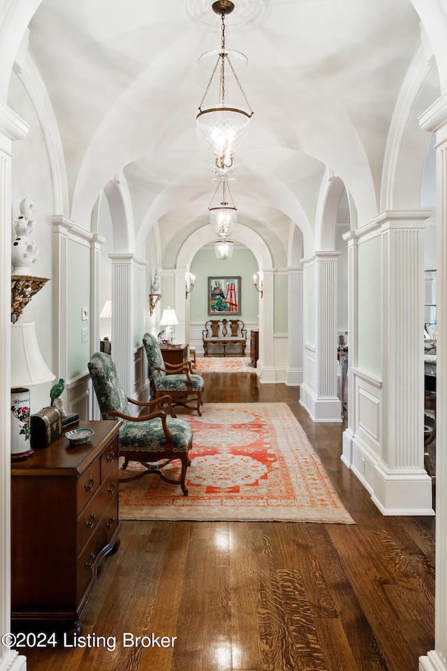 hall featuring decorative columns, vaulted ceiling, and dark wood-type flooring