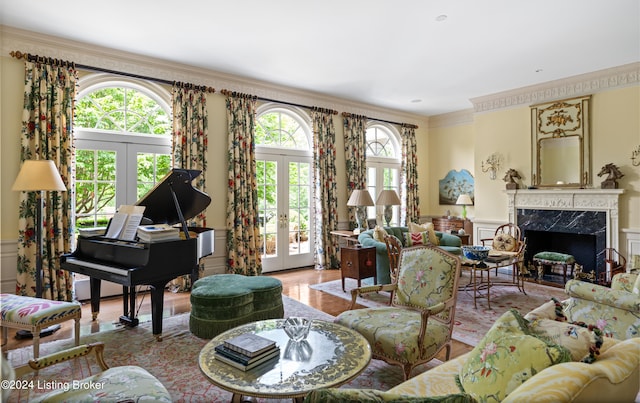 living room with french doors, light hardwood / wood-style floors, a premium fireplace, and ornamental molding