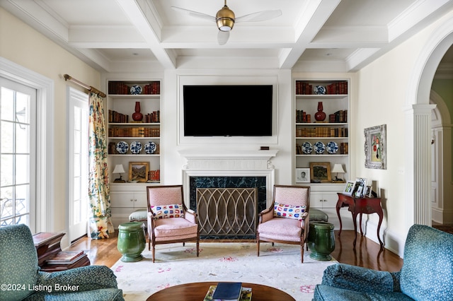 living room featuring ceiling fan, coffered ceiling, built in shelves, and hardwood / wood-style floors