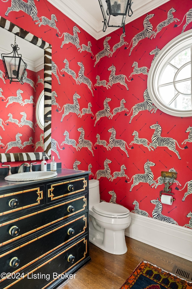 bathroom featuring vanity, ornamental molding, wood-type flooring, and toilet