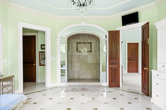 interior space with an inviting chandelier, crown molding, a shower with shower door, and decorative columns