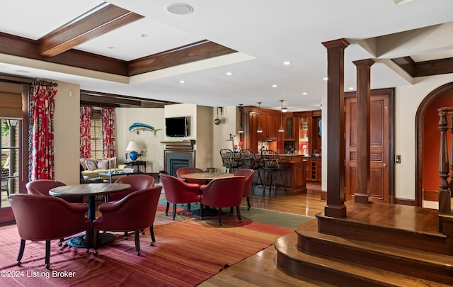 dining area with hardwood / wood-style floors, beamed ceiling, and ornate columns