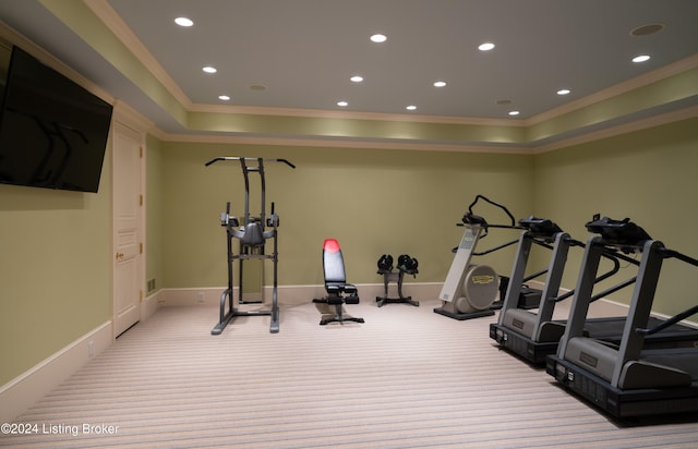 workout room featuring light carpet, ornamental molding, and a tray ceiling