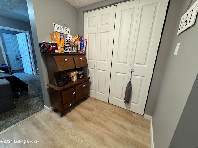 hallway featuring light hardwood / wood-style flooring and a textured ceiling