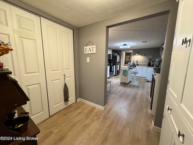 hallway featuring a textured ceiling and light wood-type flooring