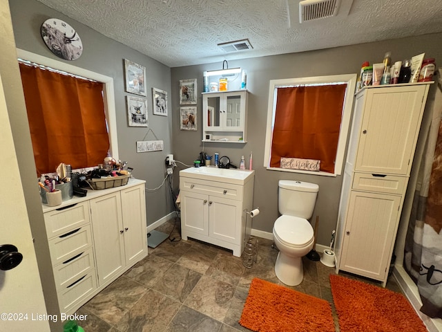 bathroom featuring vanity, curtained shower, a textured ceiling, and toilet