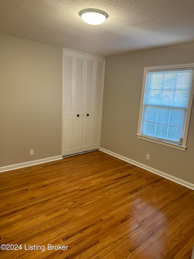 unfurnished bedroom with a closet, hardwood / wood-style flooring, and a textured ceiling