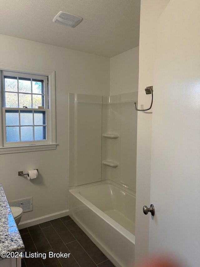 full bathroom with vanity, a textured ceiling, toilet, and shower / bath combination