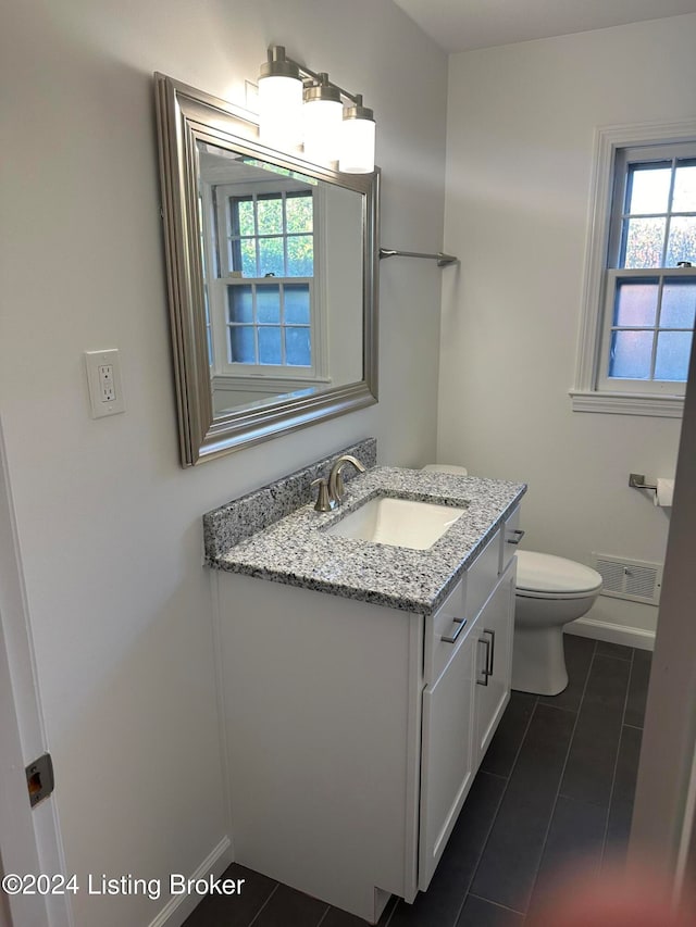 bathroom with toilet, vanity, and tile patterned flooring