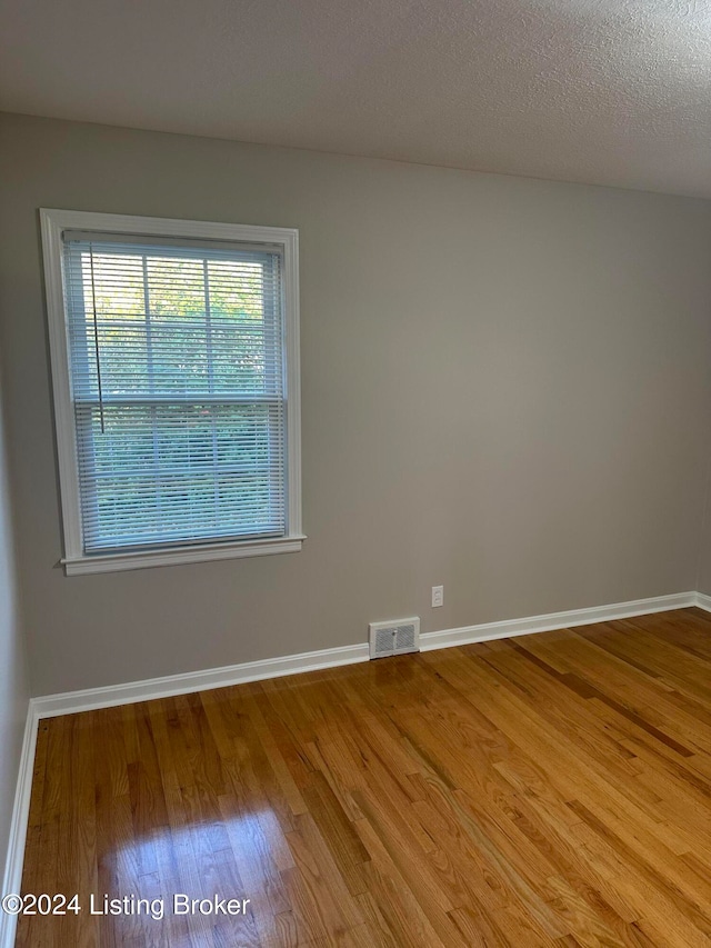 empty room featuring a textured ceiling and hardwood / wood-style floors