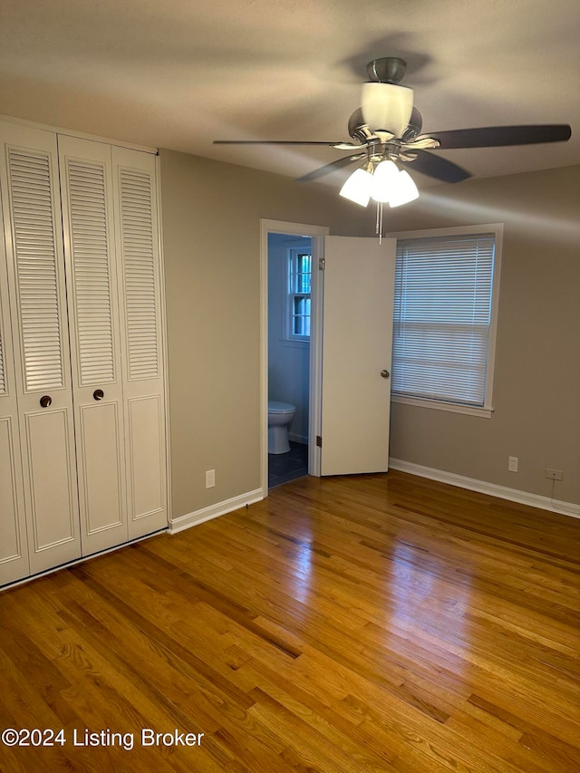 unfurnished bedroom with ensuite bath, a closet, light wood-type flooring, and ceiling fan