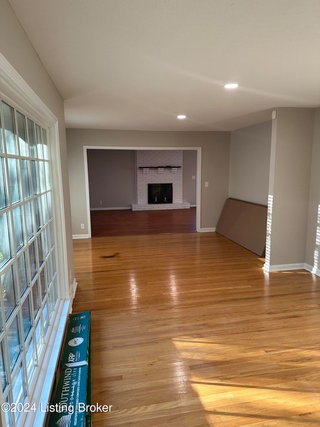 unfurnished living room with light hardwood / wood-style flooring and a brick fireplace