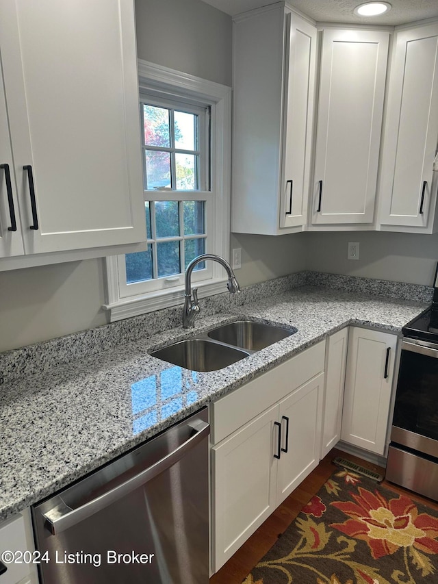 kitchen with white cabinetry, light stone counters, stainless steel appliances, and sink