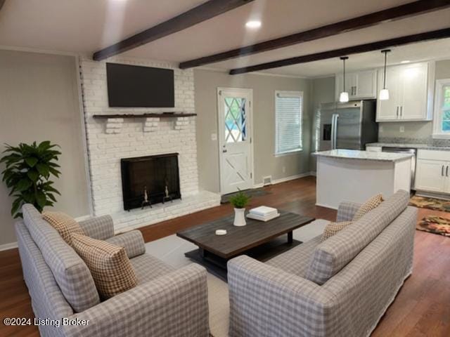 living room with ornamental molding, dark hardwood / wood-style floors, beam ceiling, and a brick fireplace