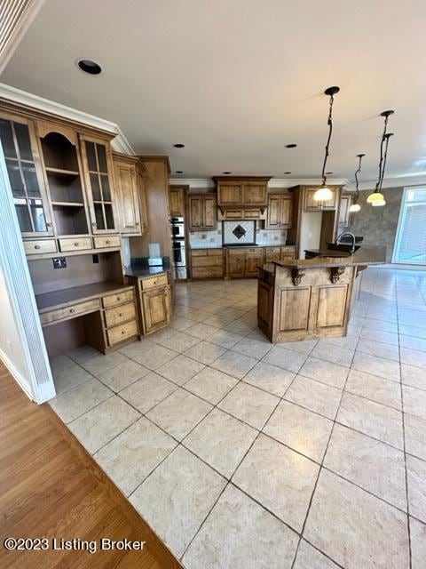 kitchen featuring a large island, ornamental molding, light tile patterned floors, and hanging light fixtures