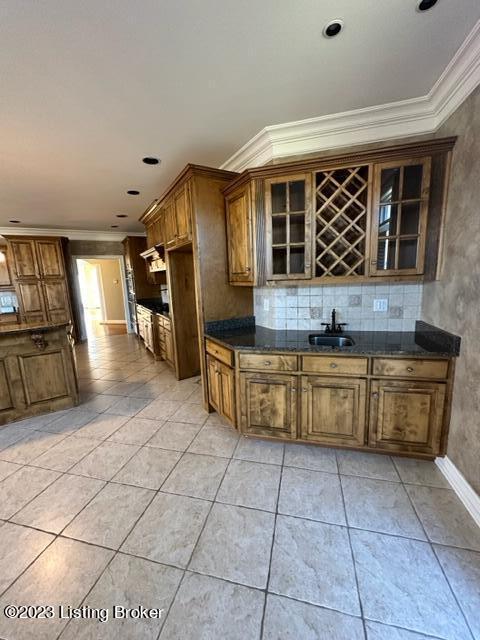 kitchen featuring tasteful backsplash, sink, ornamental molding, light tile patterned floors, and ventilation hood