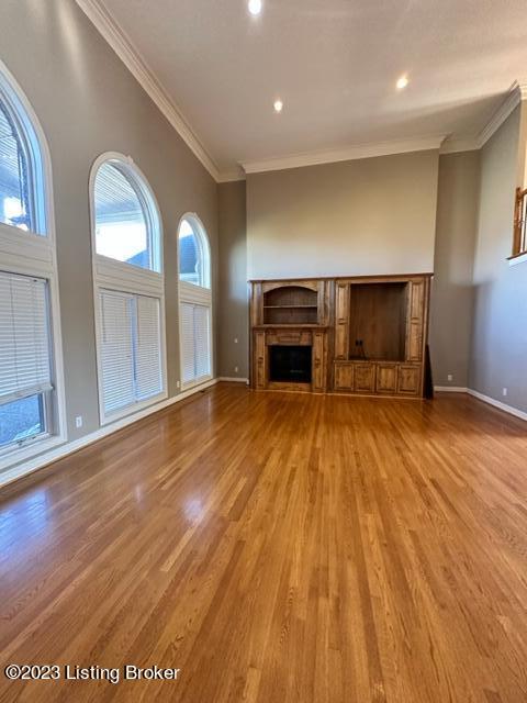 unfurnished living room featuring hardwood / wood-style floors and crown molding