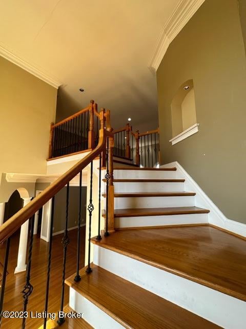 stairway featuring ornamental molding and wood-type flooring