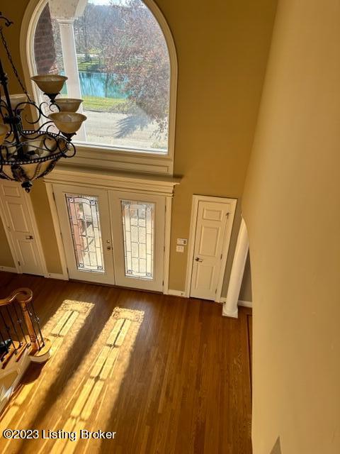 doorway with a towering ceiling, french doors, an inviting chandelier, and dark hardwood / wood-style flooring