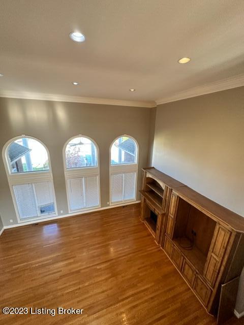 unfurnished living room with crown molding and wood-type flooring