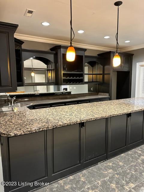 kitchen featuring stone countertops, ornamental molding, and decorative light fixtures