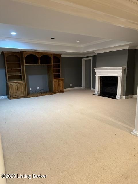 unfurnished living room featuring ornamental molding, carpet floors, and a raised ceiling