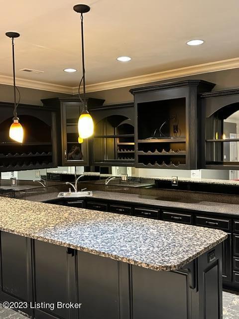 bar with sink, crown molding, light stone countertops, and hanging light fixtures