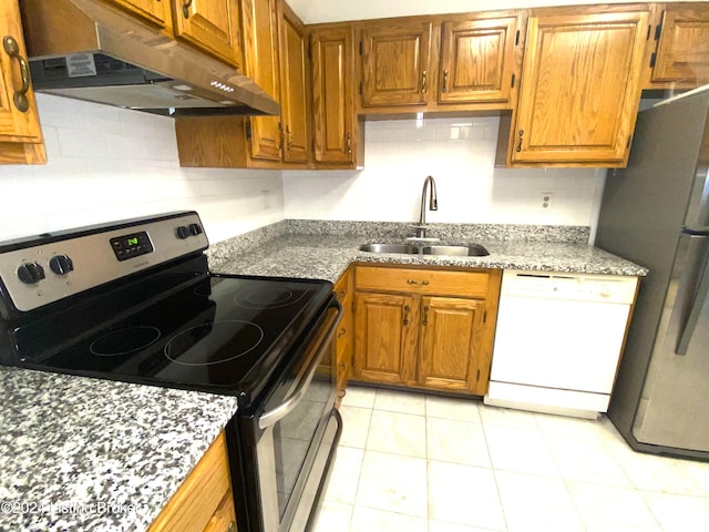 kitchen with decorative backsplash, sink, light stone countertops, light tile patterned floors, and appliances with stainless steel finishes