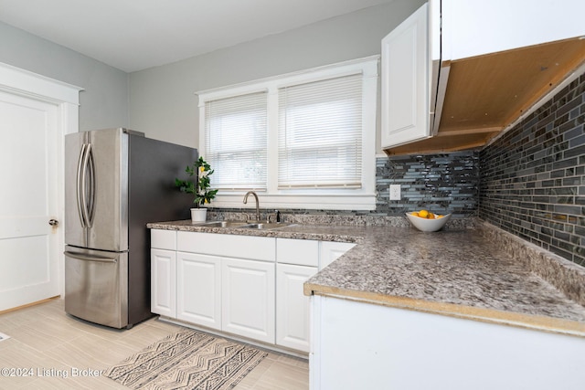 kitchen featuring white cabinetry, backsplash, sink, and stainless steel fridge