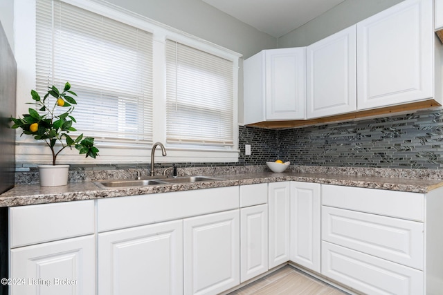 kitchen featuring white cabinetry, sink, and backsplash