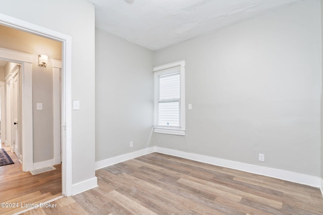 unfurnished room featuring a textured ceiling and light hardwood / wood-style flooring