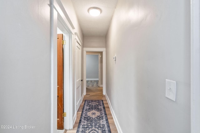 corridor featuring wood-type flooring and a textured ceiling