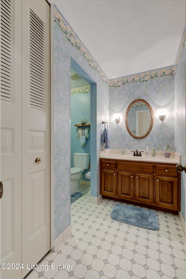 bathroom featuring toilet, a textured ceiling, and vanity