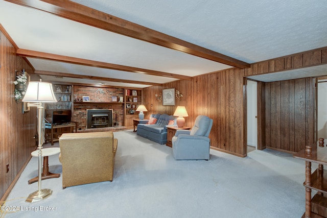 carpeted living room featuring beam ceiling, a textured ceiling, a fireplace, built in shelves, and wooden walls