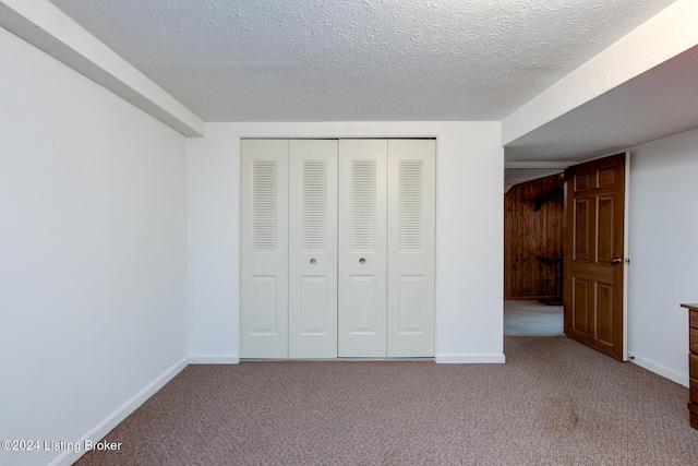 unfurnished bedroom with light carpet, a textured ceiling, and a closet