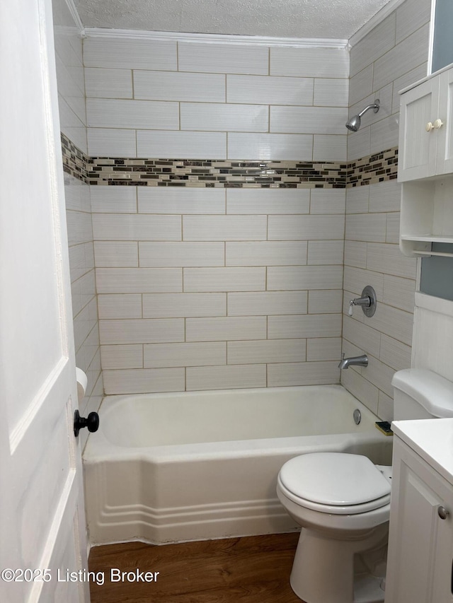 full bathroom with wood-type flooring, tiled shower / bath, toilet, a textured ceiling, and vanity