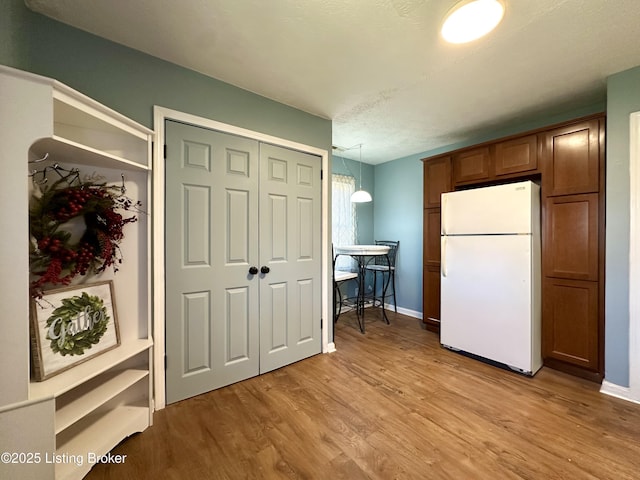 kitchen with white refrigerator, light hardwood / wood-style flooring, and pendant lighting