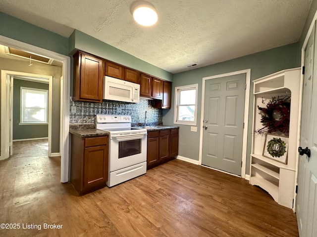 kitchen featuring hardwood / wood-style flooring, a textured ceiling, white appliances, and decorative backsplash